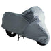 otorcycle stored outdoors with a protective grey cover